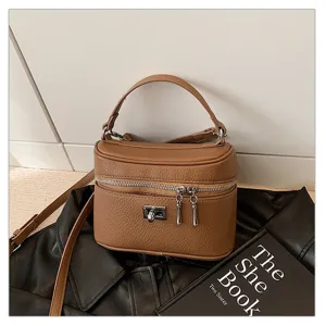 Close-up detail view of a stylish brown leather box handbag highlighting metal hardware.