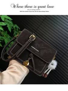 Retro leather shoulder bag detail showing exquisite metal buckle and cute plush doll pendant.
