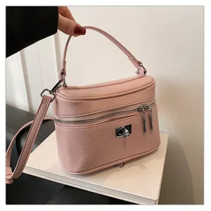 Closeup detail of the stylish pink leather vanity crossbody bag, featuring metal lock and zipper.