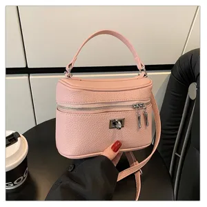 Close-up detail of a pink leather box handbag with silver hardware and lock closure.