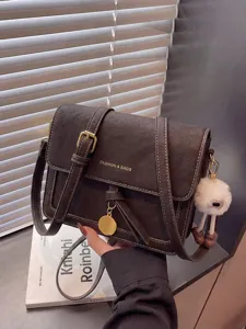 Detailed view of vintage brown crossbody bag with metal buckle and cute plush pendant.