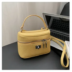 Detailed view of the yellow leather top handle box bag with metal lock in office setting.
