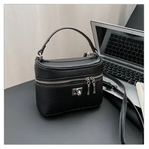 Black leather vanity handbag with top handle, metal lock, and zipper for women commute.
