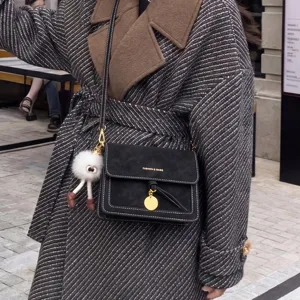 Chic black crossbody shoulder bag detail with gold ring lock, white stitching and cute charm.
