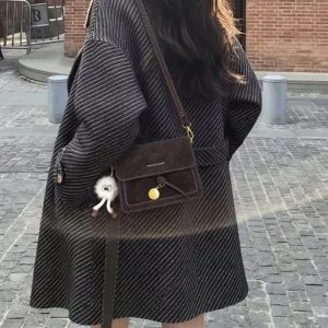 Vintage brown suede crossbody bag with gold round pendant and cute plush doll keychain detail.