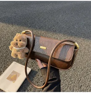 Stylish retro brown baguette shoulder bag for women, featuring a cute fluffy bear pendant.