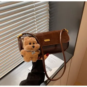 Close-up detail of the brown retro underarm shoulder bag with a cute plush dog keychain.