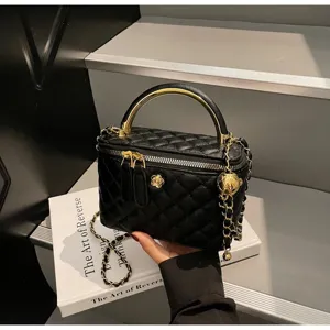 Detailed shot of a black quilted vanity bag with gold chain handle and hardware in interior.