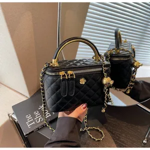 Classic quilted black vanity crossbody bag with metal top handle and gold chain strap details.