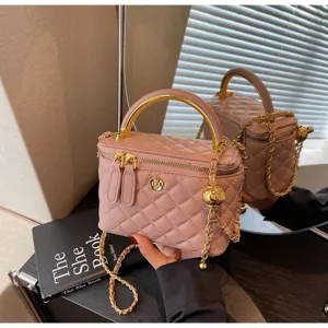 Pink quilted vanity bag detail showcasing gold metal top handle and elegant chain strap.