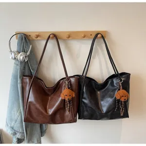Detailed view of casual PU leather tote bag hanging on wooden wall hook with cute dog charm.