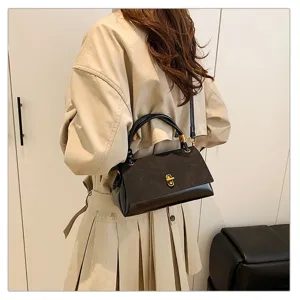 Detailed view of women's black shoulder bag with gold lock, worn on body showing style.