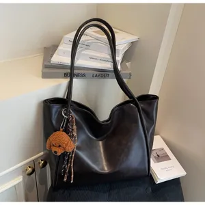 Detail shot of vintage dark tote bag with cute poodle charm in cozy interior setting.