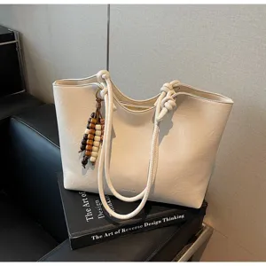 Minimalist cream white leather tote bag with knotted handles and vintage wooden bead pendant.