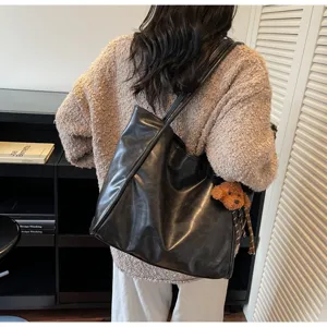 Detailed view of the stylish black oil-wax leather tote shoulder bag with a cute puppy charm.