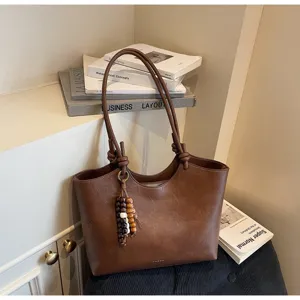Detailed view of the retro brown tote bag showcasing fine leather texture and cute wooden beads.