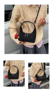 Detailed view of casual black hobo shoulder bag with cute red pom-pom charm and dual zippers.