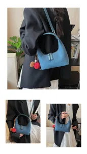 Detail view of a blue suede hobo shoulder bag with pom pom charms, stylish commuting style.