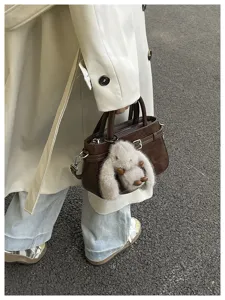 Close-up detail of the stylish brown tote bag with cute fluffy bunny pendant and strap.