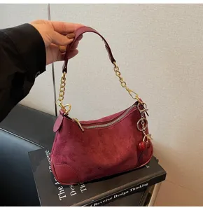 Detailed view of the vintage burgundy suede shoulder bag with gold chain and cute cherry charm.