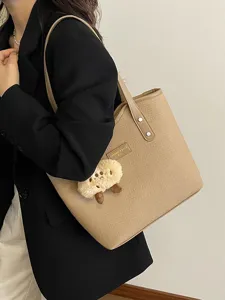 Detail view of women large capacity PU leather tote bag with cute plush charm for commute.