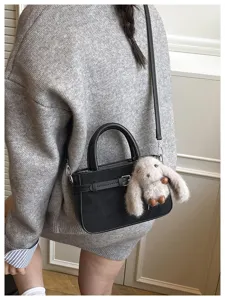 Detailed view of women's autumn winter black crossbody handbag with cute plush rabbit charm.