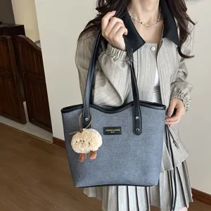 Detail view of the stylish woven PU tote bag with comfortable handles and cute plush charm.