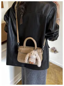 Detail view of stylish commuter crossbody bag with cute plush rabbit charm and sleek design.