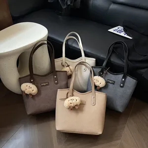 Detail shot of large capacity PU leather tote bags in multiple colors with cute pendants.