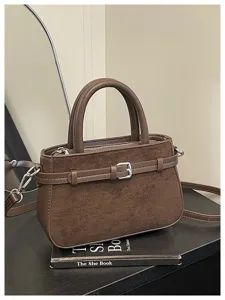 Brown suede texture handbag detail, elegant buckle strap decoration and shoulder strap design.