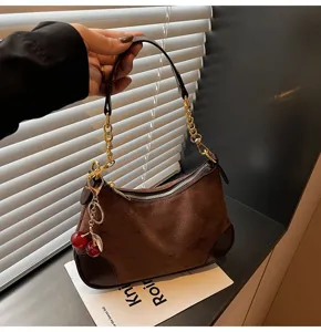 Retro brown suede shoulder bag with gold chain strap and cute cherry charm detail.