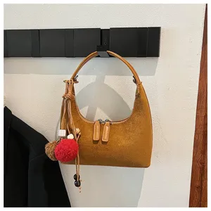 Brown suede hobo shoulder bag detail, stylish dumpling purse with fluffy pom-pom charm.