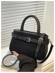Black suede handbag detail showing metal buckle strap and texture, elegant design.