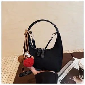 Black suede dumpling bag detail, retro hobo shoulder bag with cute pompom charm and top handle.