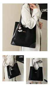 Black suede tote bag detail view highlighting the sleek metal bar accent and adorable puppy charm.