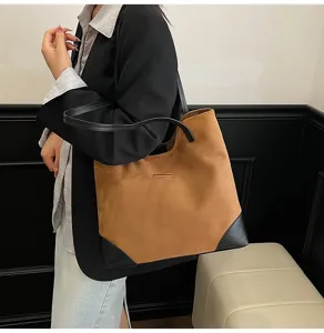Brown suede tote bag detail featuring contrast black leather corners and comfortable shoulder strap.