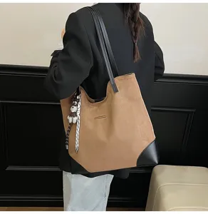 Details of the casual brown suede tote bag showing shoulder straps and stylish charm accessory.