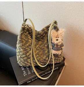 Detailed view of green fuzzy shoulder bag with cute plush charm and double straps.