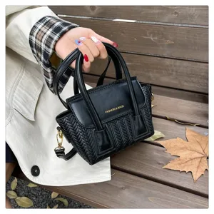 Bolso de mano negro de cuero trenzado con asas y correa, vista de detalle elegante.