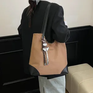 Detail view of the brown suede tote bag with black corners and cute dog keychain accessory.