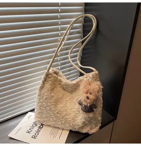 Close-up shot of fluffy plush shoulder bag featuring cute teddy bear pendant and thin straps.
