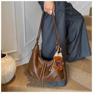Brown PU leather shoulder bag detail with cute teddy bear charm and elegant bow ribbon.