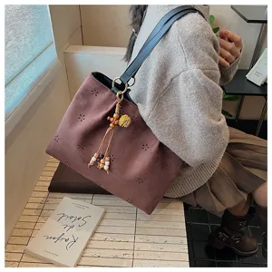 Nahaufnahme der braunen Wildleder-Tasche mit Blumen-Ausschnitt und Holzperlen-Quaste.