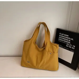 Detailed view of casual yellow oxford cloth tote bag with large capacity and shoulder strap.