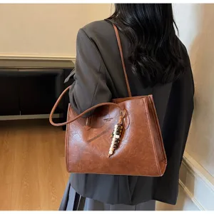 Retro brown PU leather tote bag with charm, casual large capacity commuting shoulder handbag.