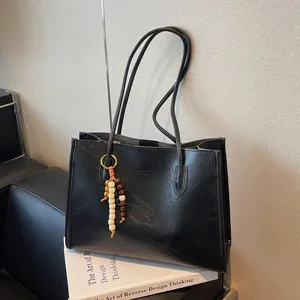 Black large capacity shoulder tote bag for women commuting, vintage PU leather handbag with charm.