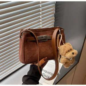 Vintage brown suede Kelly shoulder bag with metal lock and cute plush dog charm detail.