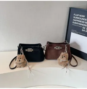 Suede shoulder bag featuring metal turn-lock closure and cute plush bear pendant detail.