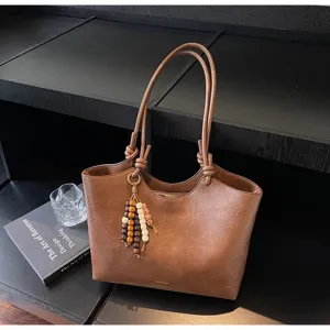 Brown PU leather tote bag detail, featuring double shoulder straps with knot and wooden bead charm.