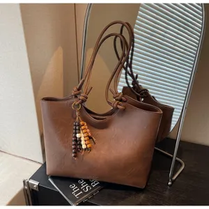 Minimalist brown PU leather tote bag with knot handles and stylish wooden bead tassel charm.